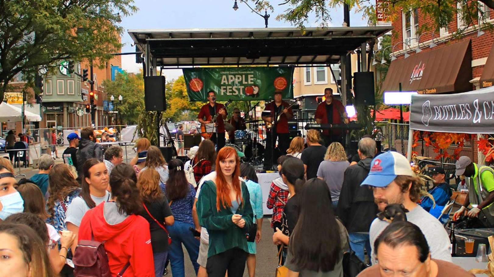The Lincoln Square Apple Fest in Chicago, Illinois, featuring a live band performing on a stage and a crowd of attendees.