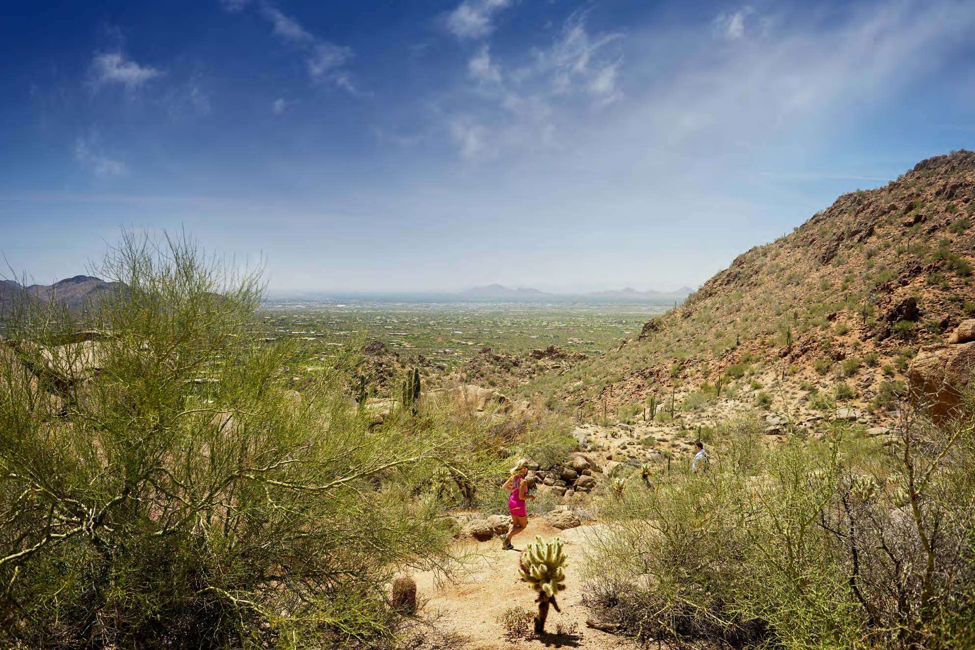 A jogger passing through a scenic area overlooking the desert and city skyline at Pinnacle Peak Park in Scottsdale, Arizona.