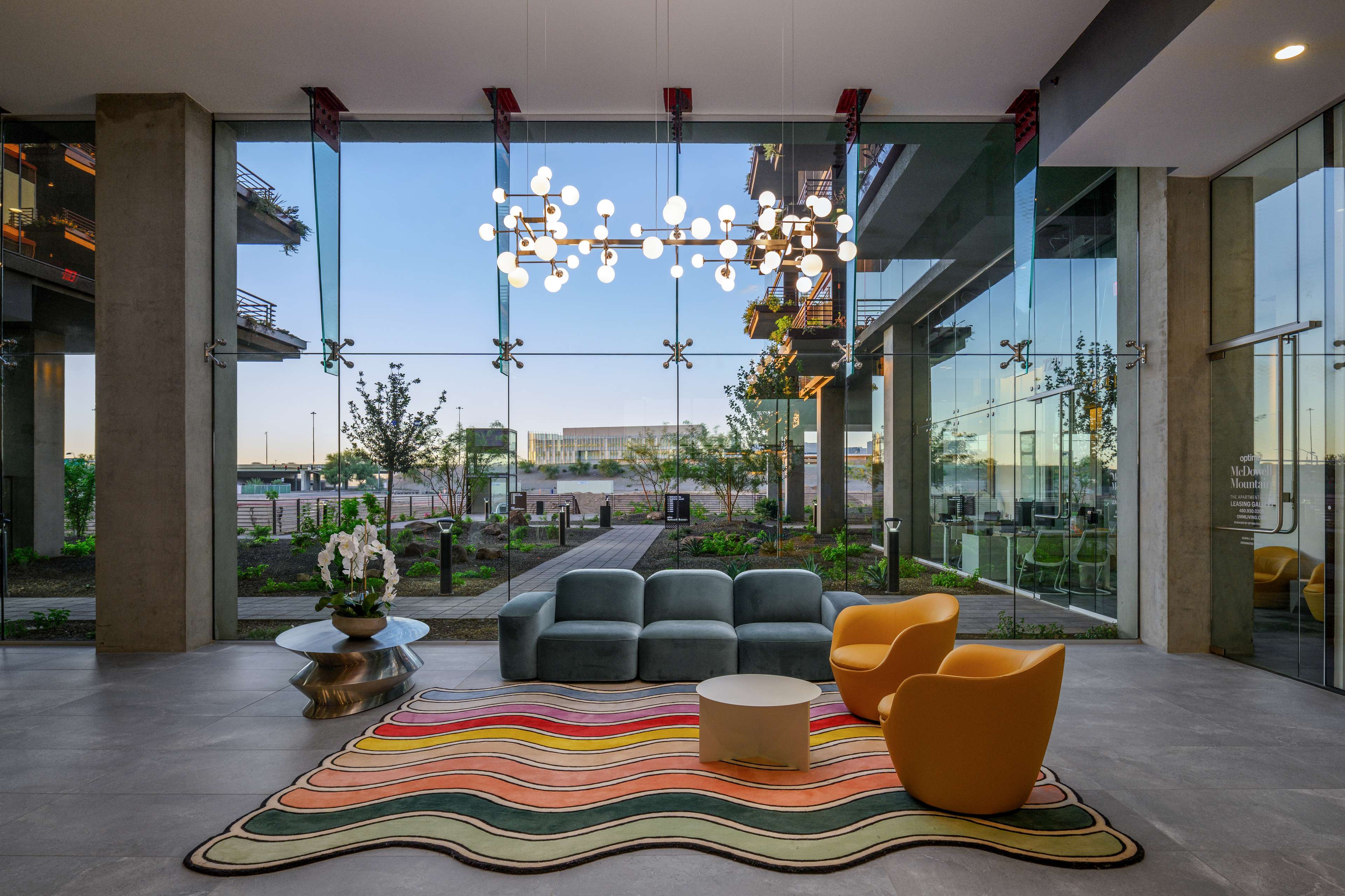 Lobby interior of Optima McDowell Mountain in Scottsdale, modern furniture among concrete columns and full length windows.