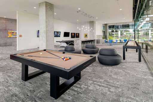 A pool table & shuffleboard table separated by modern black chairs in the resident lounge at Optima Kierland in Scottsdale.