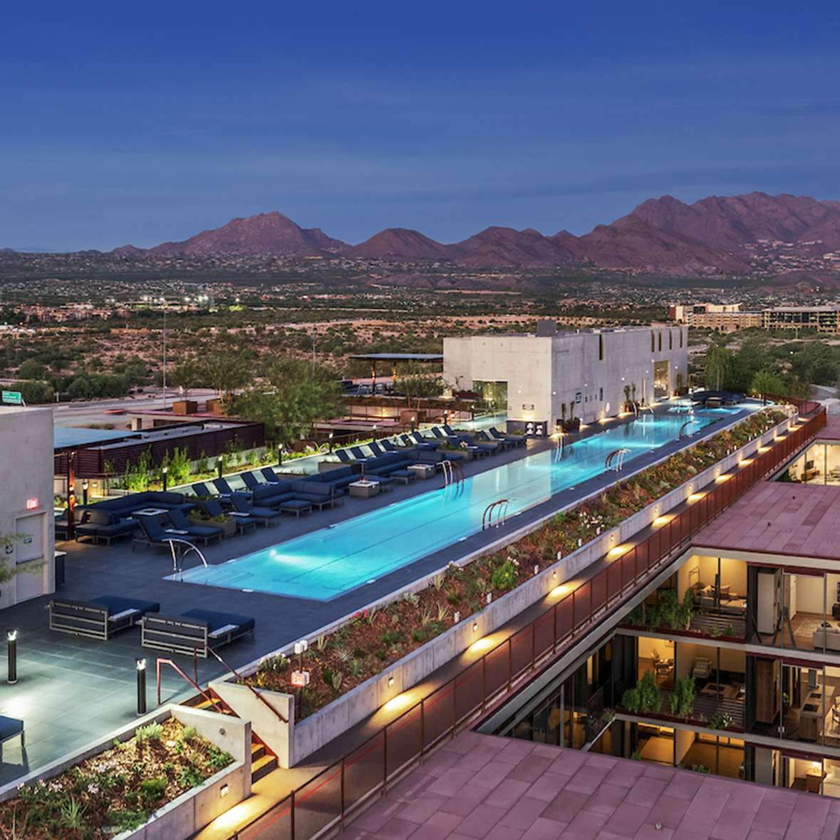Birdseye view of a rooftop shared space at Optima McDowell Mountain condominium with lap pools and lounge seating with a bbq.