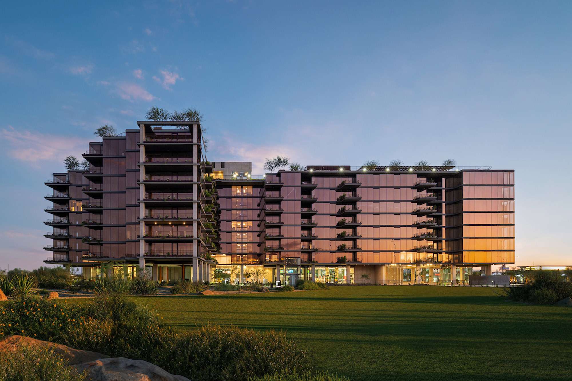 A rendering of Optima McDowell Mountain in Scottsdale, bronze-tinted full length glass windows and vertical gardens.