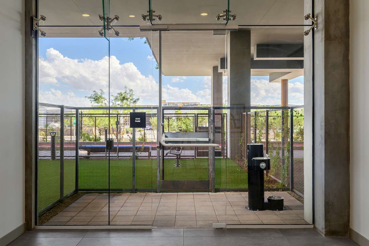 Optima Kierland Apartments in Scottsdale, Arizona, featuring a fenced outdoor dog park accessible through a glass door.