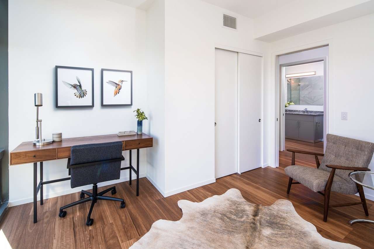 Mid-century modern home office with a walnut wood & black metal desk and two drawings of hummingbirds on the wall.