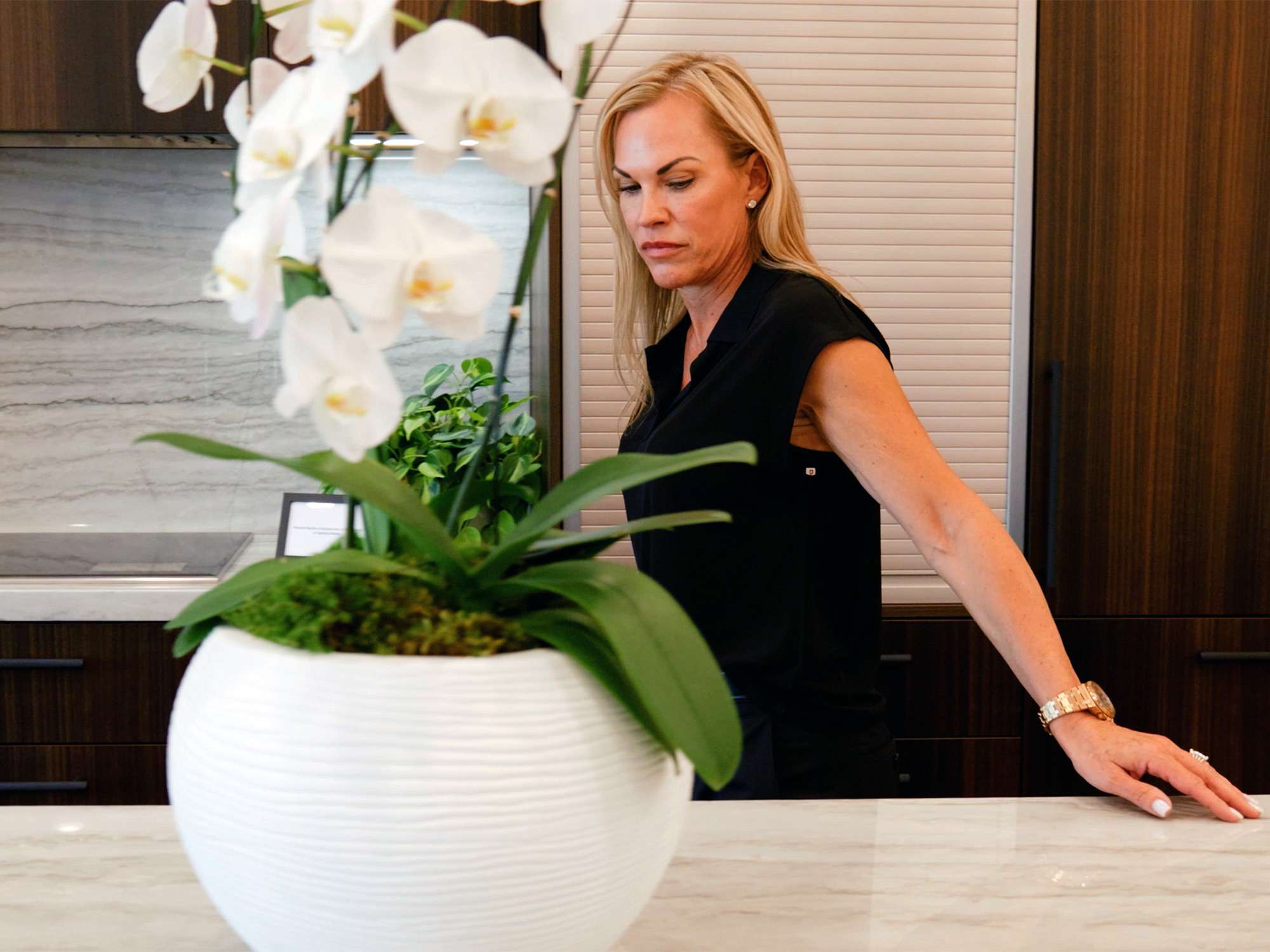 Photo of interior designer Claire Ownby staging white orchid flowers in a sclupted white pot at Optima McDowell Mountain.