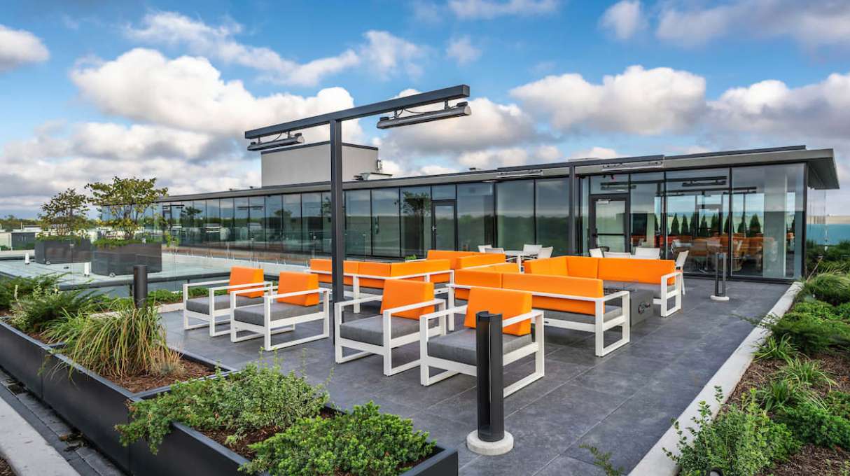 The rooftop sky deck at Optima Verdana luxury apartments in Wilmette, IL, with modern, vibrant orange lounge seating areas.
